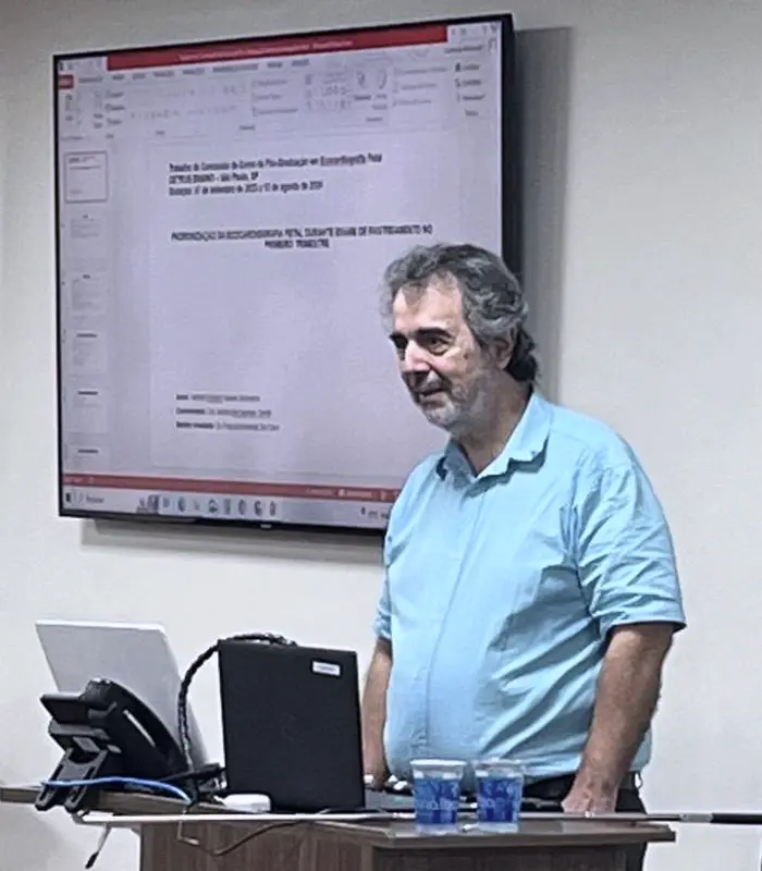 Dr. Haroldo apresentando o trabalho de conclusão da pós-graduação em Ecocardiografia Fetal, diante do slide projetado